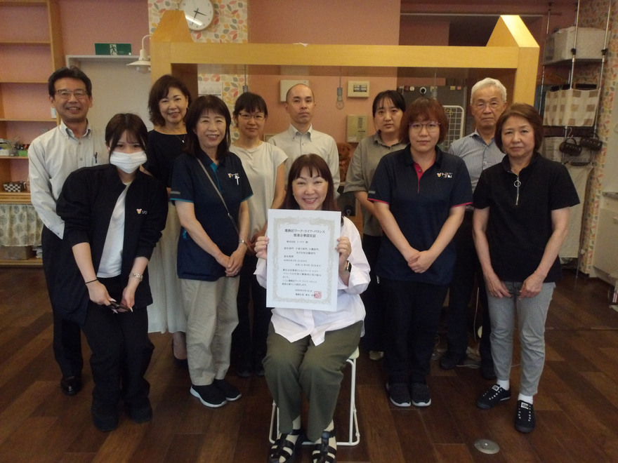 代表が認定証を掲げていて、その周りに社員が集まっている集合写真